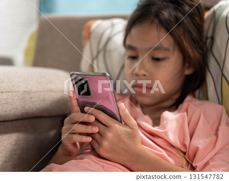 Young girl using smartphone indoors on a sofa Young girl using smartphone indoors on a sofa 131547782