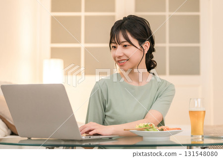 晚上在家吃飯時,年輕的亞洲女性一邊放鬆一邊看筆記型電腦 晚上在家吃飯時,年輕的亞洲女性一邊放鬆一邊看筆記型電腦 131548080