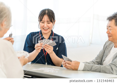 集體住宅或養老院裡的老人和一位女性護理人員打牌 131548463