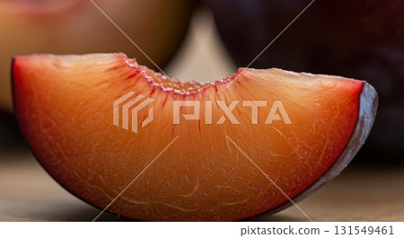Close up of a fresh plum slice showing vibrant red and orange flesh texture 131549461