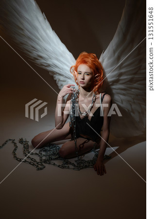Beauty woman with angel wings poses in studio setting Beauty woman with angel wings poses in studio setting 131551648