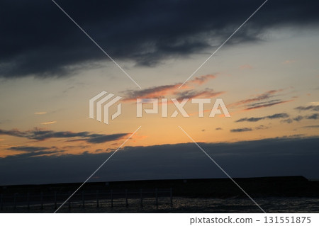 大海、防波堤、雲彩和橘色天空的傍晚景色 大海、防波堤、雲彩和橘色天空的傍晚景色 131551875