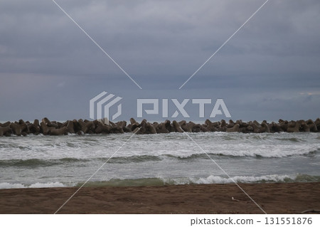 沙灘、海浪拍打的海岸、四足動物破碎機、大海和多雲的天空的風景 131551876