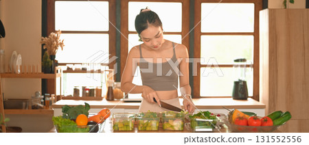 Woman chopping broccoli and dividing food into meals weekend meal prep for weight loss. 131552556