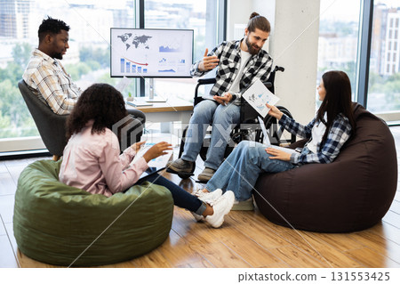 Group of diverse professionals engaged in team discussion analyzing reports in modern workspace. 131553425