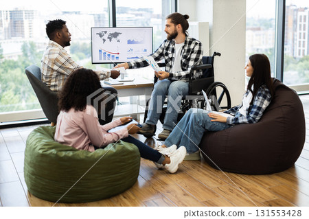 Group of four people, diverse backgrounds, discussing finances and strategies in modern, relaxed workspace with charts Group of four people, diverse backgrounds, discussing finances and strategies in modern, relaxed workspace with charts 131553428