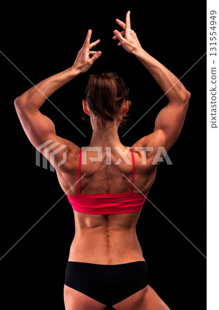 Strong woman with muscular body posing against black background 131554949