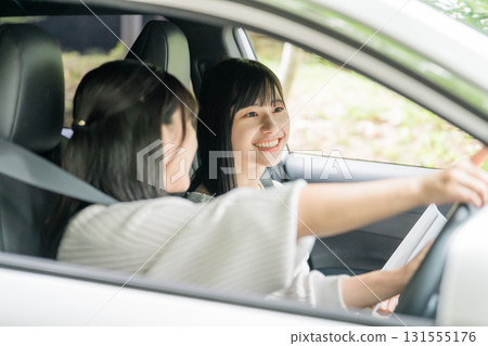 A female driver driving a car and her female friend in the passenger seat A female driver driving a car and her female friend in the passenger seat 131555176