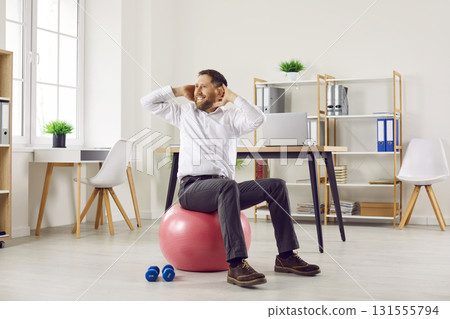 Funny young business man doing sport exercises sitting on fit ball in office. Funny young business man doing sport exercises sitting on fit ball in office. 131555794