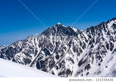 The summit of Mount Tsurugi seen from the hiking trail of Mount Oku-Dainichi. Climbing Mount Oku-Dainichi in the Northern Alps during the snowy season. The summit of Mount Tsurugi seen from the hiking trail of Mount Oku-Dainichi. Climbing Mount Oku-Dainichi in the Northern Alps during the snowy season. 131556436
