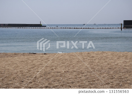 A landscape of a sandy beach, blue sea, jetty, float, fishing boat, horizon and blue sky 131556563