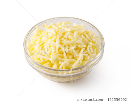 Grated cheese overflowing a small glass bowl on white background Grated cheese overflowing a small glass bowl on white background 131556992