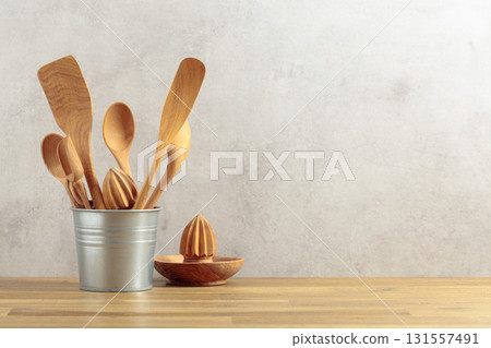 Wooden kitchen utensils in small bucket on a kitchen table. Wooden kitchen utensils in small bucket on a kitchen table. 131557491
