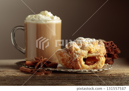 Viennese strudel and coffee latte on an old wooden table. Viennese strudel and coffee latte on an old wooden table. 131557587