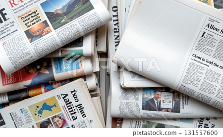 A collection of newspapers spread out in various stacks and piles 131557600