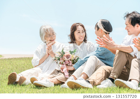 一個可以看到藍天的公園，一個坐在山上的家庭，父母和孩子，一個三代家庭（父親，母親，女兒，祖母，祖父） 131557720