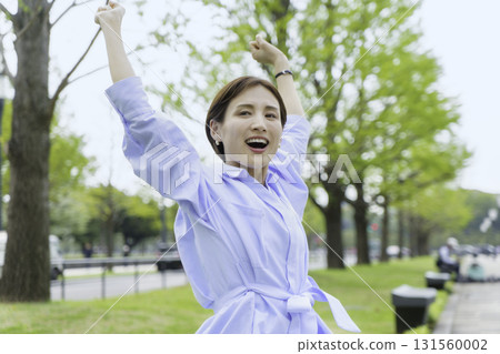 Portrait of a young businesswoman sitting and stretching in a park in an office district 131560002