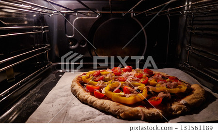 A freshly baked pizza with colorful toppings inside an oven. The crust is golden brown, and the toppings include bell peppers and tomatoes. A freshly baked pizza with colorful toppings inside an oven. The crust is golden brown, and the toppings include bell peppers and tomatoes. 131561189