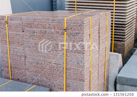 Pallets with stacked gray paving slabs selective focus Stack of paving slabs in warehouse road repair or finished tile sale space for text. High quality photo 131561208