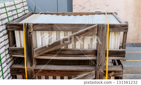Pallets with stacked gray paving slabs selective focus Stack of paving slabs in warehouse road repair or finished tile sale space for text. High quality photo Pallets with stacked gray paving slabs selective focus Stack of paving slabs in warehouse road repair or finished tile sale space for text. High quality photo 131561232
