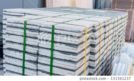 Pallets with stacked gray paving slabs selective focus Stack of paving slabs in warehouse road repair or finished tile sale space for text. High quality photo Pallets with stacked gray paving slabs selective focus Stack of paving slabs in warehouse road repair or finished tile sale space for text. High quality photo 131561237
