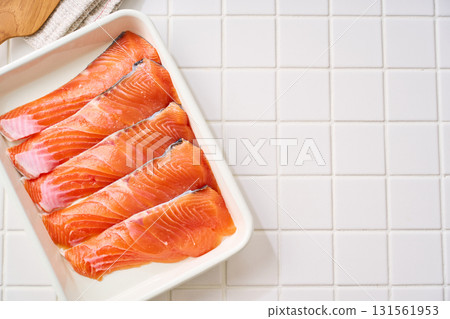 Raw salmon fillets | Cooking ingredients arranged on a white tray (tile background) Raw salmon fillets | Cooking ingredients arranged on a white tray (tile background) 131561953