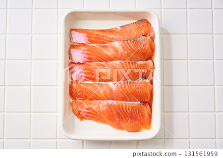 Raw salmon fillets | Cooking ingredients arranged on a white tray (tile background) Raw salmon fillets | Cooking ingredients arranged on a white tray (tile background) 131561959