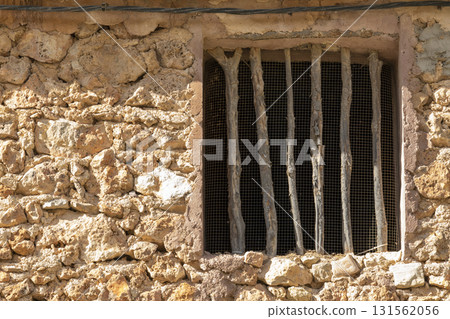 A window with bars on it is shown in a stone building 131562056