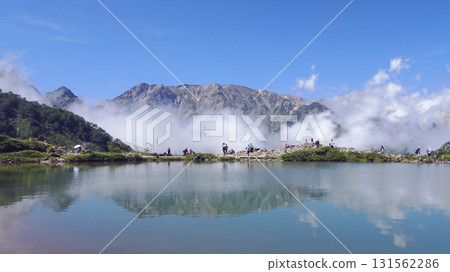 Hakuba mountain range and hikers reflected in Happoike Pond [Chubu Sangaku National Park] Hakuba Village, Nagano Prefecture 131562286