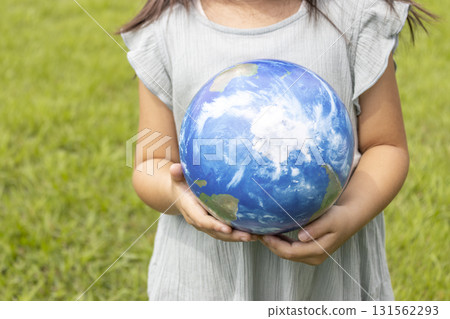 一個女孩站在草地上，手裡拿著地球儀（5歲，日本人，無臉） 131562293