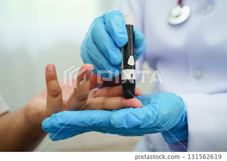 Asian woman self testing to check blood sugar level diabetes by digital lancet on finger at home. 131562619