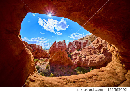 Red Rock Arch Framing Sun and Desert Landscape in Dramatic Nevada Scenery 131563092