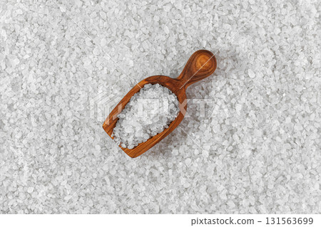 Coarse sea salt crystals in wooden scoop with forming textured background Coarse sea salt crystals in wooden scoop with forming textured background 131563699