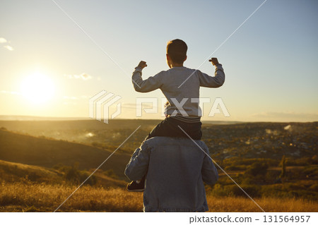 Child boy sitting on fathers shoulders and looking into the distance enjoying sunset outdoors 131564957