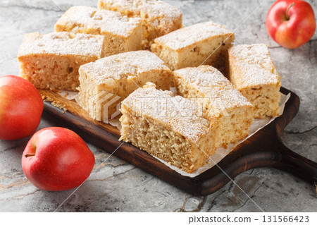 Autumn American Applesauce cake dusted with powdered sugar close-up on a wooden board. Horizontal 131566423