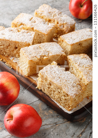 Applesauce cake with ginger sprinkled with powdered sugar close-up on a wooden board. Vertical Applesauce cake with ginger sprinkled with powdered sugar close-up on a wooden board. Vertical 131566426