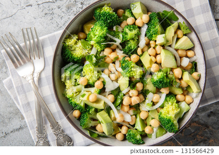 hearty, balanced salad of broccoli, chickpeas, avocado, onion, and parsley with a lemon oil dressing, close-up in a bowl. Horizontal top view 131566429