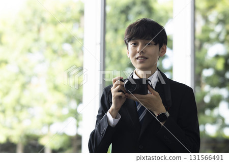 Man in a suit holding a camera 131566491