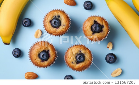 Banana fruit slice, blueberry almond topping on muffin cake cup on blue background Banana fruit slice, blueberry almond topping on muffin cake cup on blue background 131567203