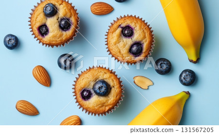 Banana fruit slice, blueberry almond topping on muffin cake cup on blue background Banana fruit slice, blueberry almond topping on muffin cake cup on blue background 131567205