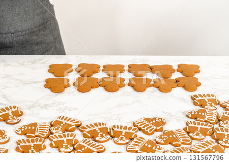 A neat arrangement of gingerbread girl cookies, fully decorated with white royal icing, placed in rows on a marble countertop. A neat arrangement of gingerbread girl cookies, fully decorated with white royal icing, placed in rows on a marble countertop. 131567796