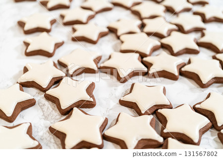 A close-up view of gingerbread star cookies with smooth white royal icing, highlighting the intricate details of the festive cookies. A close-up view of gingerbread star cookies with smooth white royal icing, highlighting the intricate details of the festive cookies. 131567802