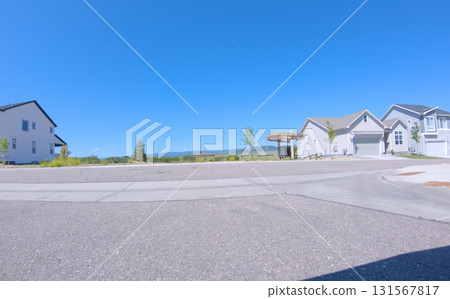 A wide cul-de-sac in a residential area of Castle Rock, Colorado showing new homes and an open blue sky. The pavement is clean and the street curves gently toward distant houses. 131567817
