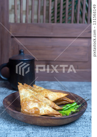 Crispy Martabak Tahu or Indonesian tofu filled fritters on a wooden plate, served with fresh green chilies, perfect for a snack or appetizer. Crispy Martabak Tahu or Indonesian tofu filled fritters on a wooden plate, served with fresh green chilies, perfect for a snack or appetizer. 131568149