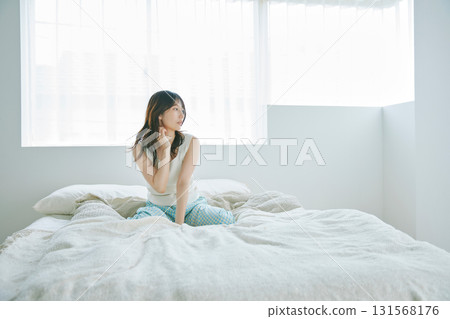 A woman sitting on a bed A woman sitting on a bed 131568176