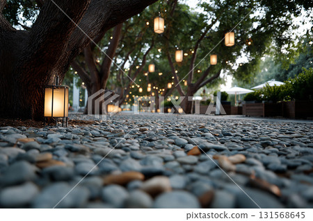 Serene stone pebble path under trees with lanterns floating low, creating tranquil and inviting atmosphere. soft glow of lanterns enhances peaceful setting 131568645