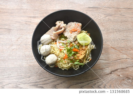 dry Chinese egg yellow noodles topping boiled chop pork with pork ball dressing cayenne pepper couple shrimp on bowl 131568685