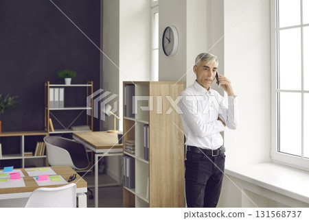 Senior businessman is busy talking on a mobile phone solving various problems at work. Senior businessman is busy talking on a mobile phone solving various problems at work. 131568737