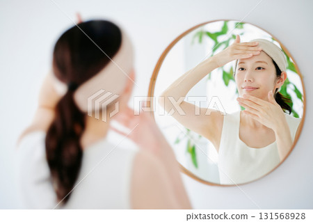 A woman checking the condition of her skin in the mirror 131568928