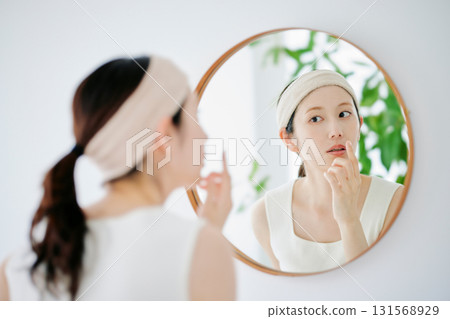 A woman checking the condition of her skin in the mirror 131568929